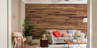Pine Wood Stipes Interior wallpaper in walnut tones behind a grey sofa and sheepskin armchair in a living room