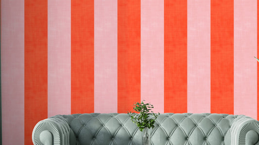 Pink and Red Stripes Linen Texture wallpaper behind a sage green tufted sofa with a glass vase in a living room