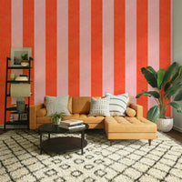 Pink and Red Stripes Linen Texture wallpaper behind a tan leather sectional and black shelves in a living room