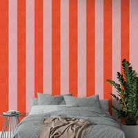 Pink and Red Stripes Linen Texture wallpaper above a gray quilted bed with a leafy plant in a bedroom