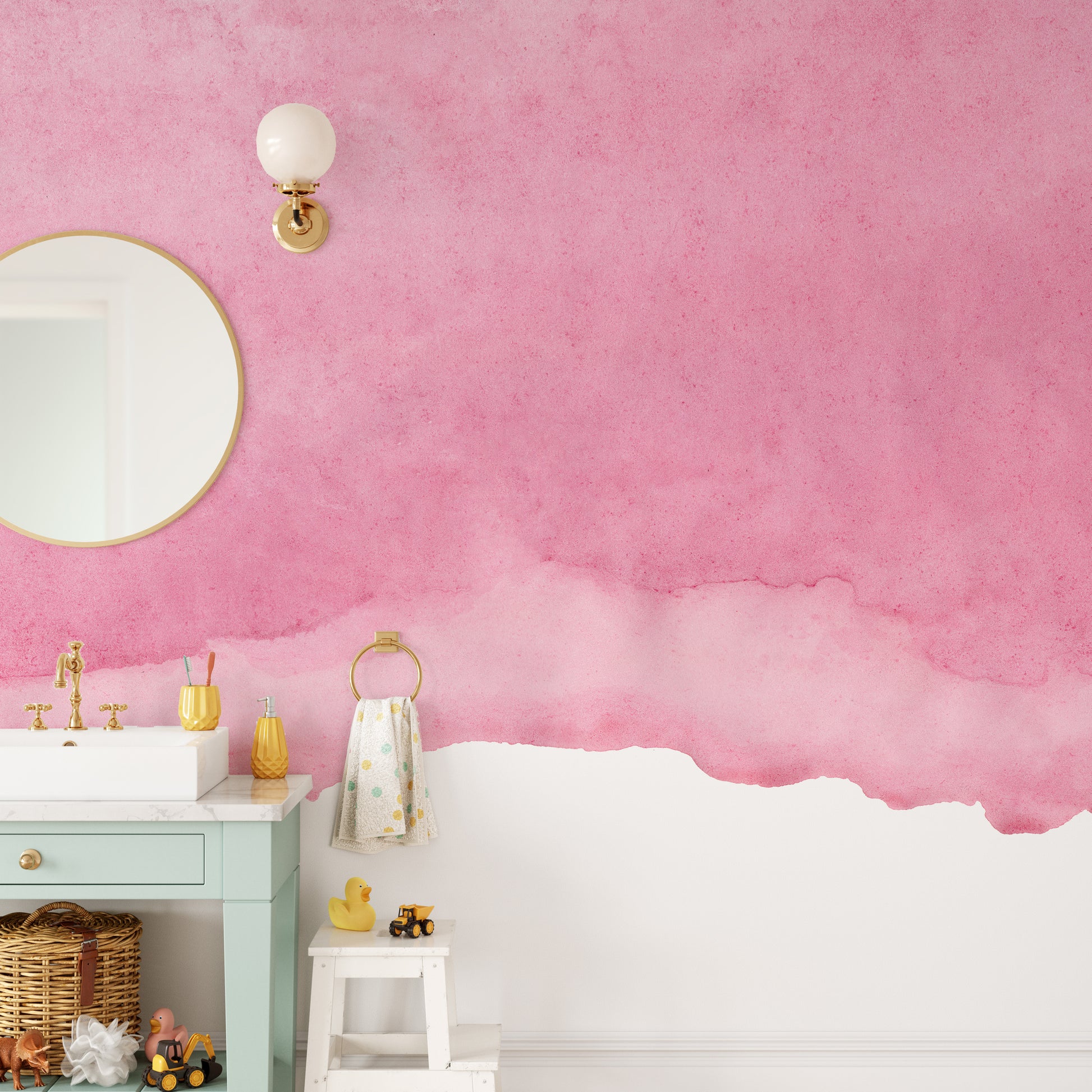 Pink shades watercolor wallpaper in a kids bathroom with a mint vanity, round mirror and rubber ducks