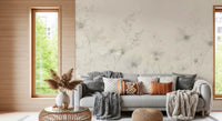 Poetic Soft Floral Linen wallpaper mural of greige flowers in a living room with a grey sofa and rust knit pillows