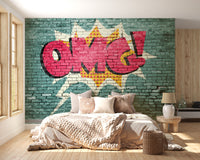 Pop Art OMG Graffiti wallpaper mural on teal brick behind a bed with cream knit bedding in a bright bedroom
