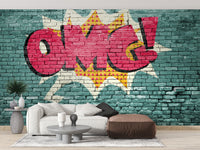 Pop Art OMG Graffiti wallpaper mural in red on a teal brick wall behind a white sofa and brown pouf in a living room
