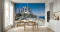 A scenic wallpaper featuring ancient Greek architecture surrounded by rugged stones and deep blue waters.