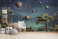 Pretty Planets wallpaper mural of planets over palms behind a white cat chair and panda bins in a kids room