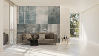 Vintage Elegance wallpaper mural in soft grey-blue tones behind a taupe sofa in a bright marble-floored living room
