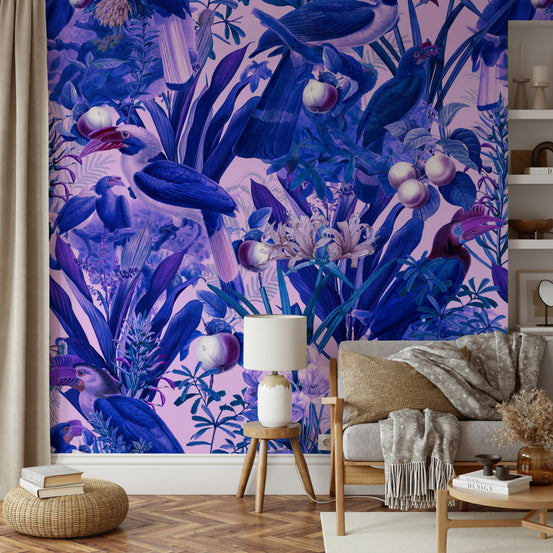 Purple Jungle wallpaper mural with blue tropical birds behind a beige sofa and tripod lamp in a living room