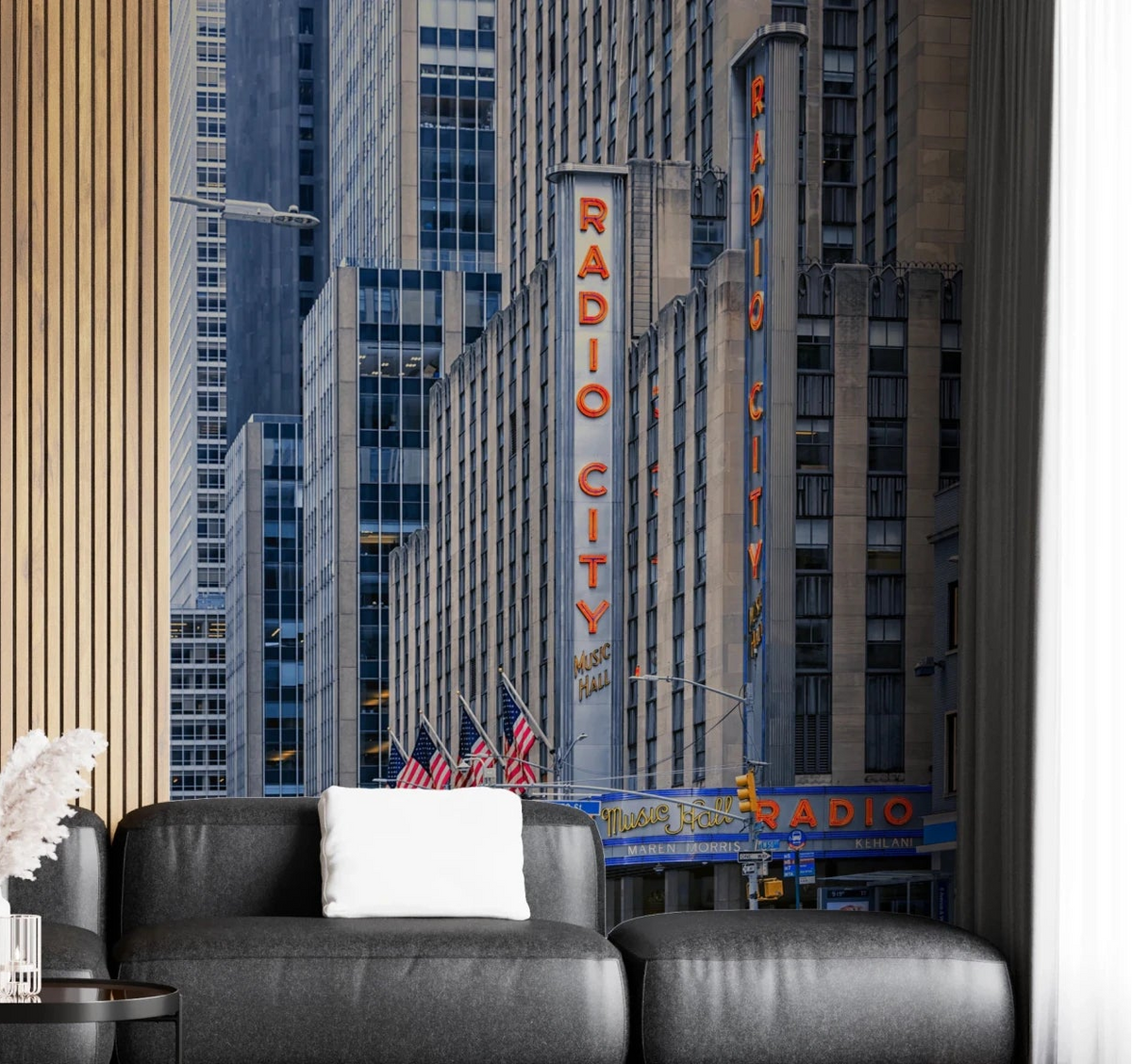 Radio City's Glow wallpaper mural with the red Radio City neon sign and skyscrapers behind a dark grey leather sofa