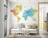 Rainbow World Map wallpaper in vivid watercolor behind a white sofa with grey chevron cushion in a Scandi living room