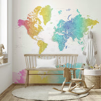 Rainbow World Map wallpaper in rainbow watercolor behind a wooden bench and rocking horse with a toy basket in a nursery