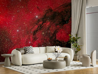 Cosmic Ember wallpaper mural of a deep red nebula behind a curved cream sofa in a sunlit living room