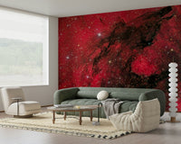 Cosmic Ember wallpaper mural with red nebula and black dust lanes above a green sofa in a modern living room
