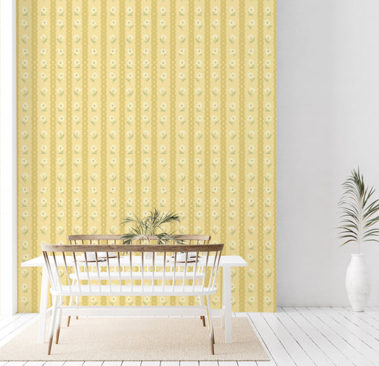 Retro Daisy Chains wallpaper mural in a dining room behind a white table and bench, yellow stripes with cream daisies