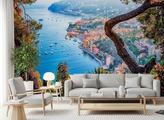 Riviera Vista wallpaper mural of a blue Mediterranean bay and coastal town behind a grey sofa in a living room