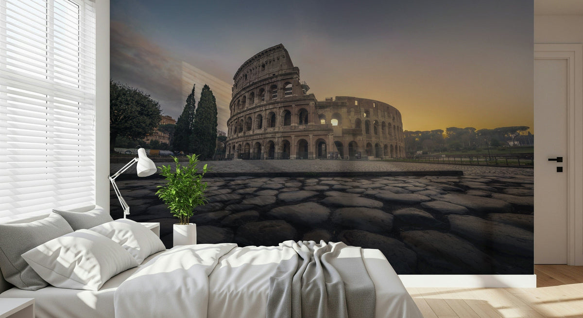 Ancient Rome Sunrise wallpaper mural of the Colosseum at golden sunrise above a white bed and reading lamp in a bedroom