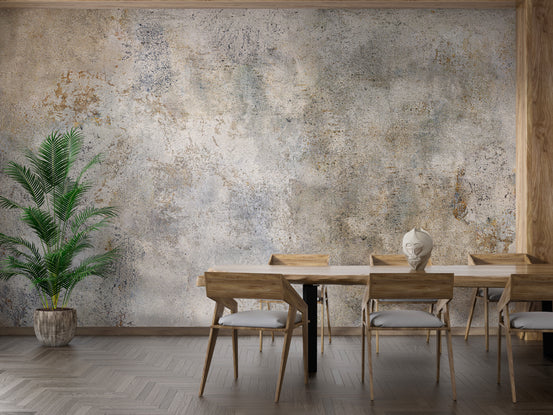 Rustic Gray Cement Texture wallpaper mural with tan patina behind a wood dining table and tall potted palm