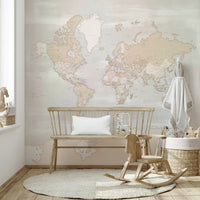 Rustic World Map wallpaper in soft beige behind a wooden bench and rocking horse with a toy basket in a nursery
