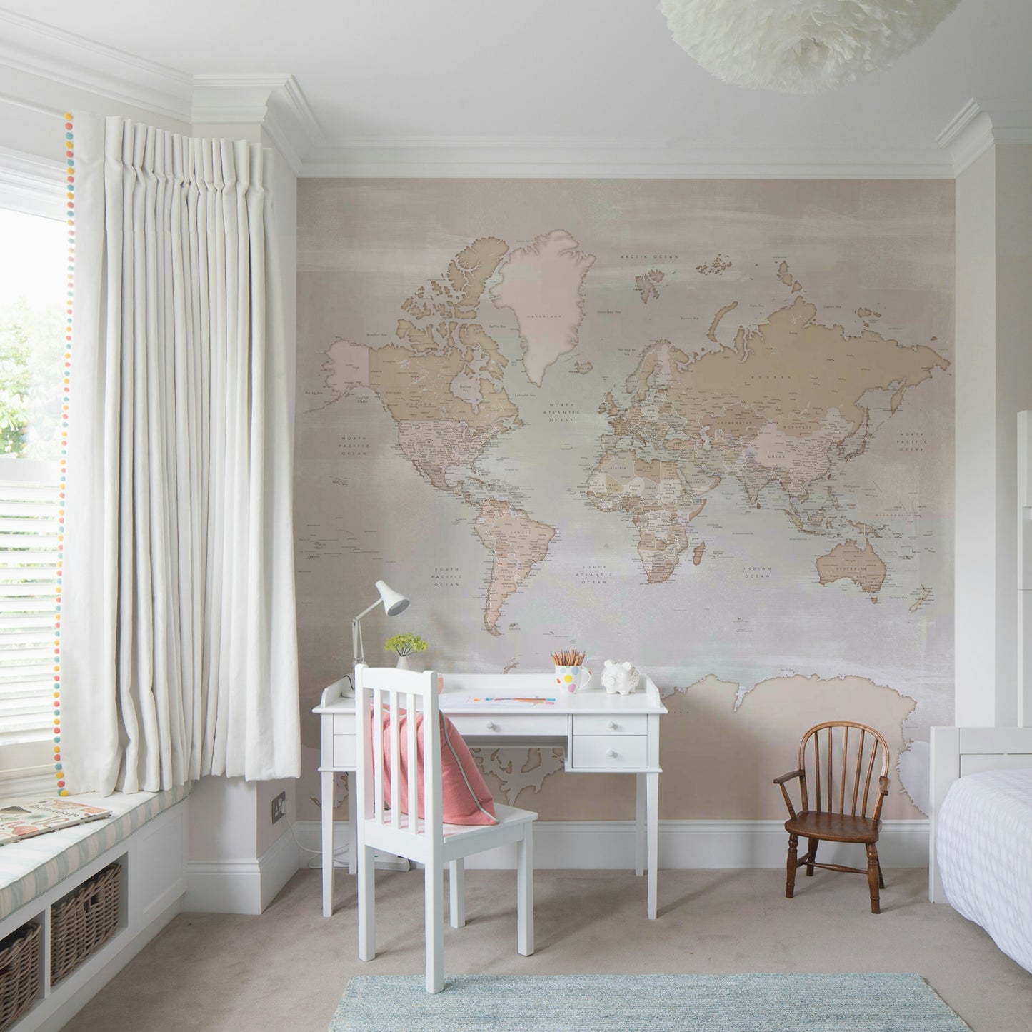 Rustic World Map wallpaper in soft beige behind a white desk and chair with a coral cushion in a girls bedroom
