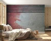 Rustic Rouge Concrete wallpaper mural in red and gray behind a low platform bed beside a wood slat panel