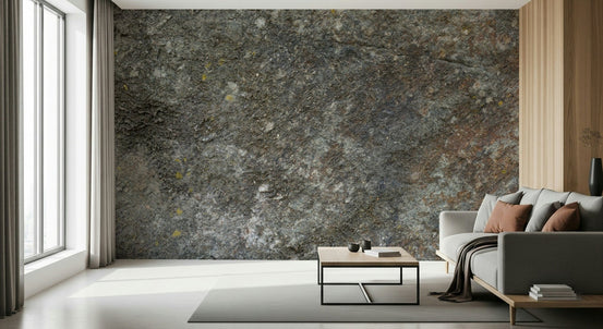 Rustic Stone wallpaper mural of weathered grey rock behind a grey sofa with rust pillows by tall windows