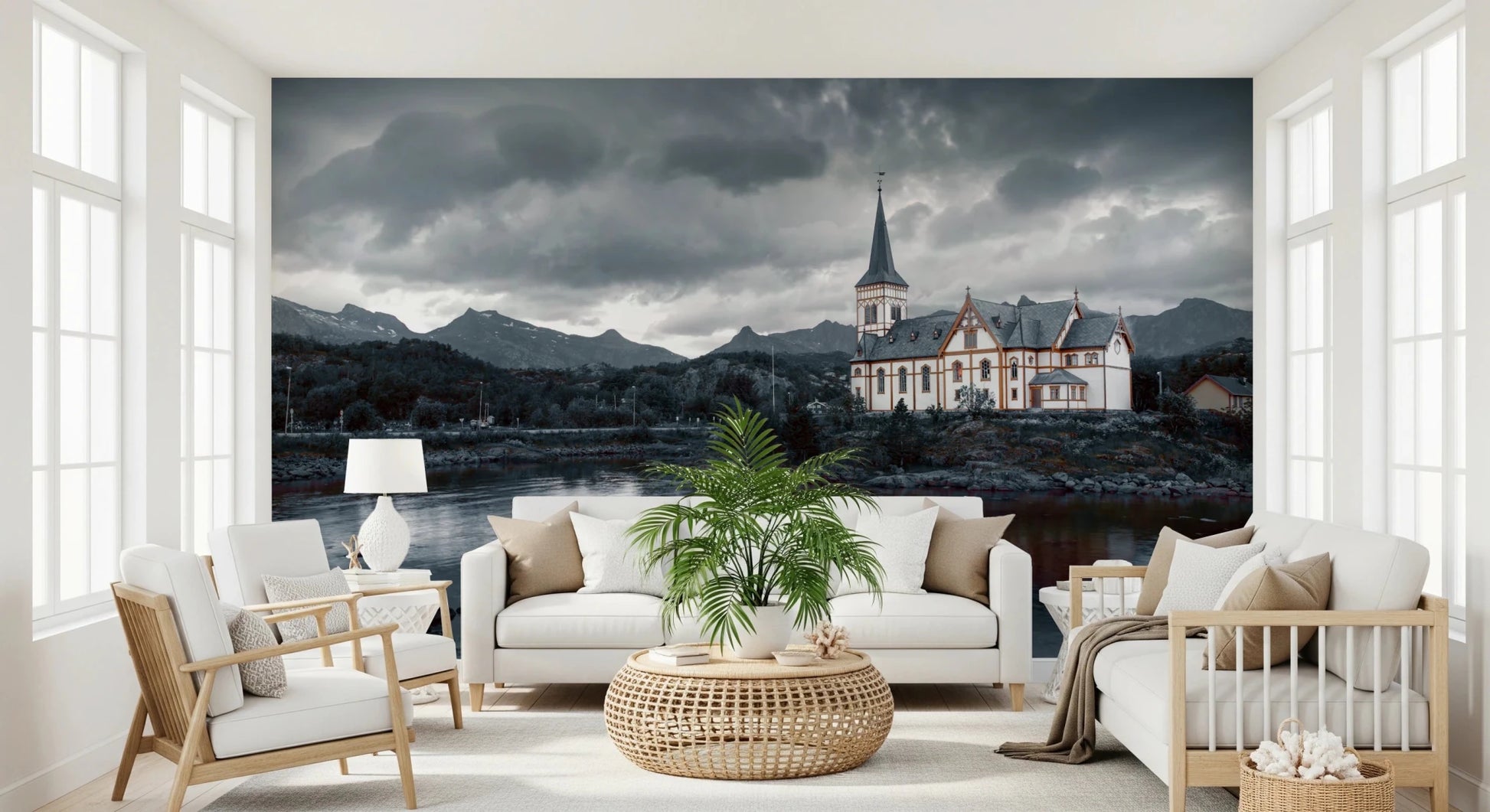 Sacred Shores wallpaper mural of a lakeside church under storm clouds behind two white sofas and a palm in a living room