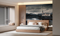 Sacred Shores wallpaper mural of a moody lakeside church above a camel leather bed in a warm modern bedroom