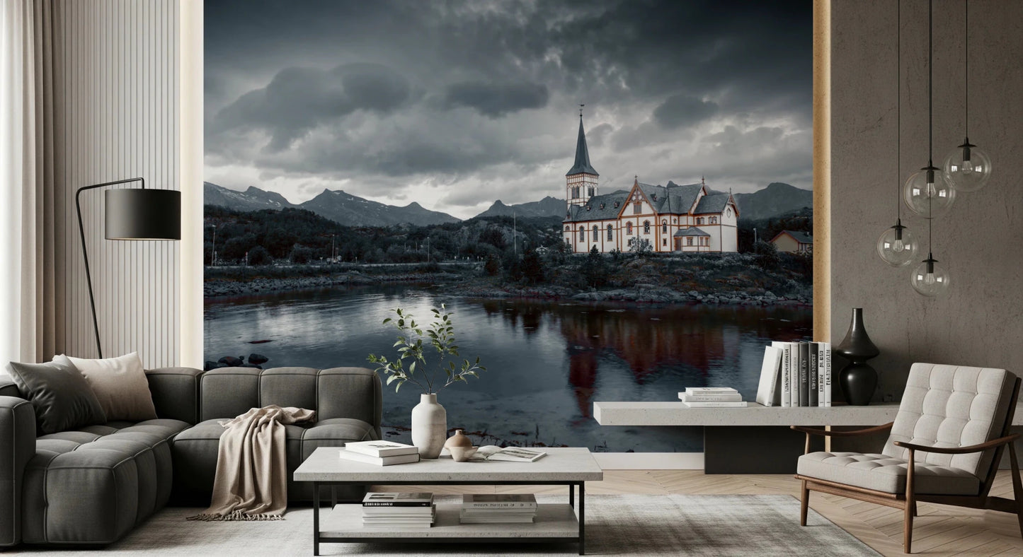 Sacred Shores wallpaper mural of a moody church and lake behind a grey sectional and tufted armchair in a living room