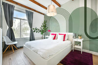 Sage Green Archways wallpaper mural in a bedroom with a white bed, hot-pink cushions and a magenta rug