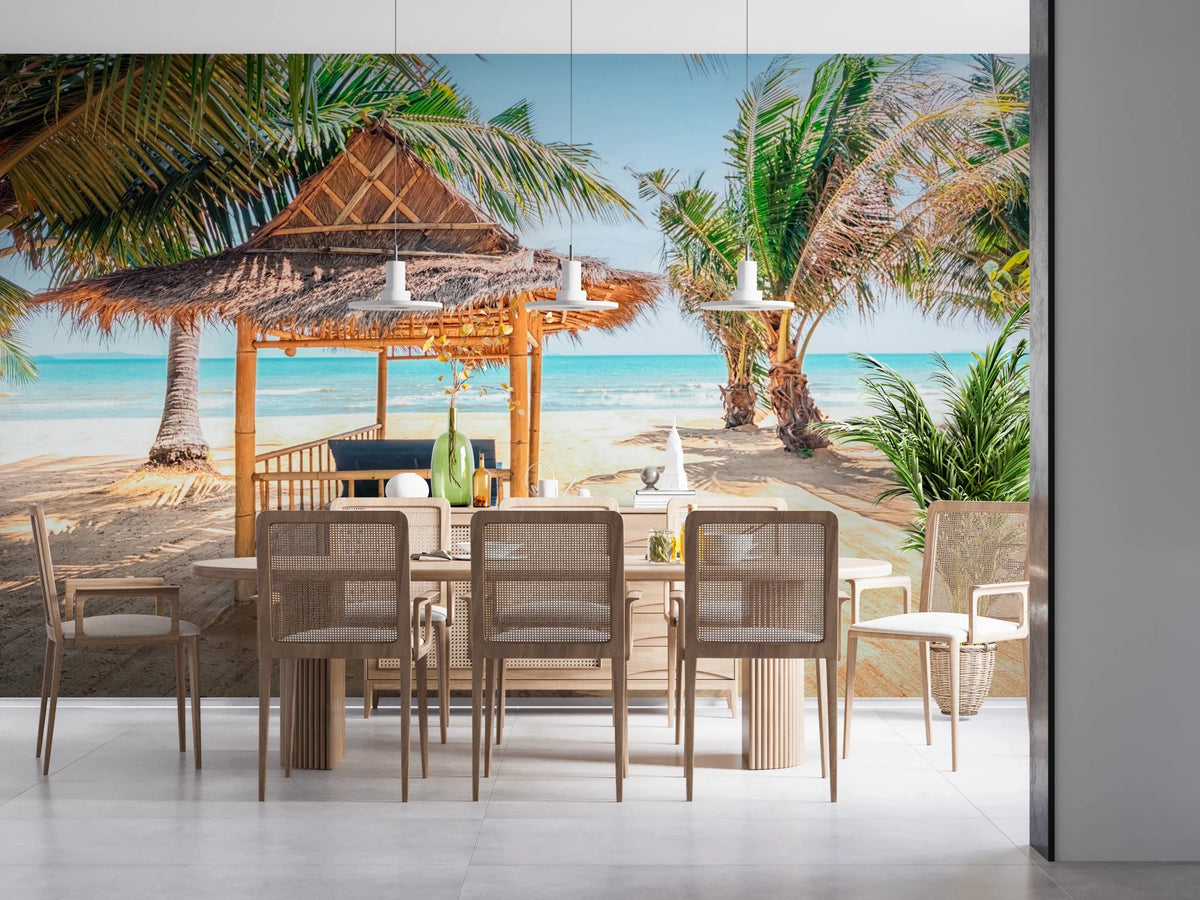Seaside Sanctuary wallpaper mural of a thatched beach cabana and palms above a wood dining table and rattan chairs