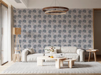 Serene Blooms wallpaper with blue blooms behind a low grey sofa under a round wood pendant light