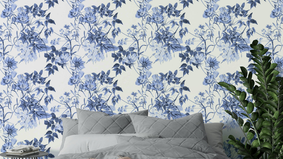 Serene Blue Botanicals wallpaper behind a bed with a grey quilted headboard and pillows in a calm bedroom