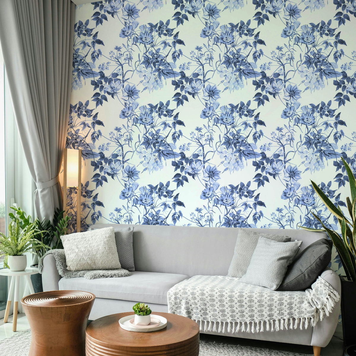 Serene Blue Botanicals wallpaper in a living room with a grey sofa and round wooden coffee tables
