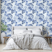 Serene Blue Botanicals wallpaper above a grey upholstered bed with white bedding and a knit throw