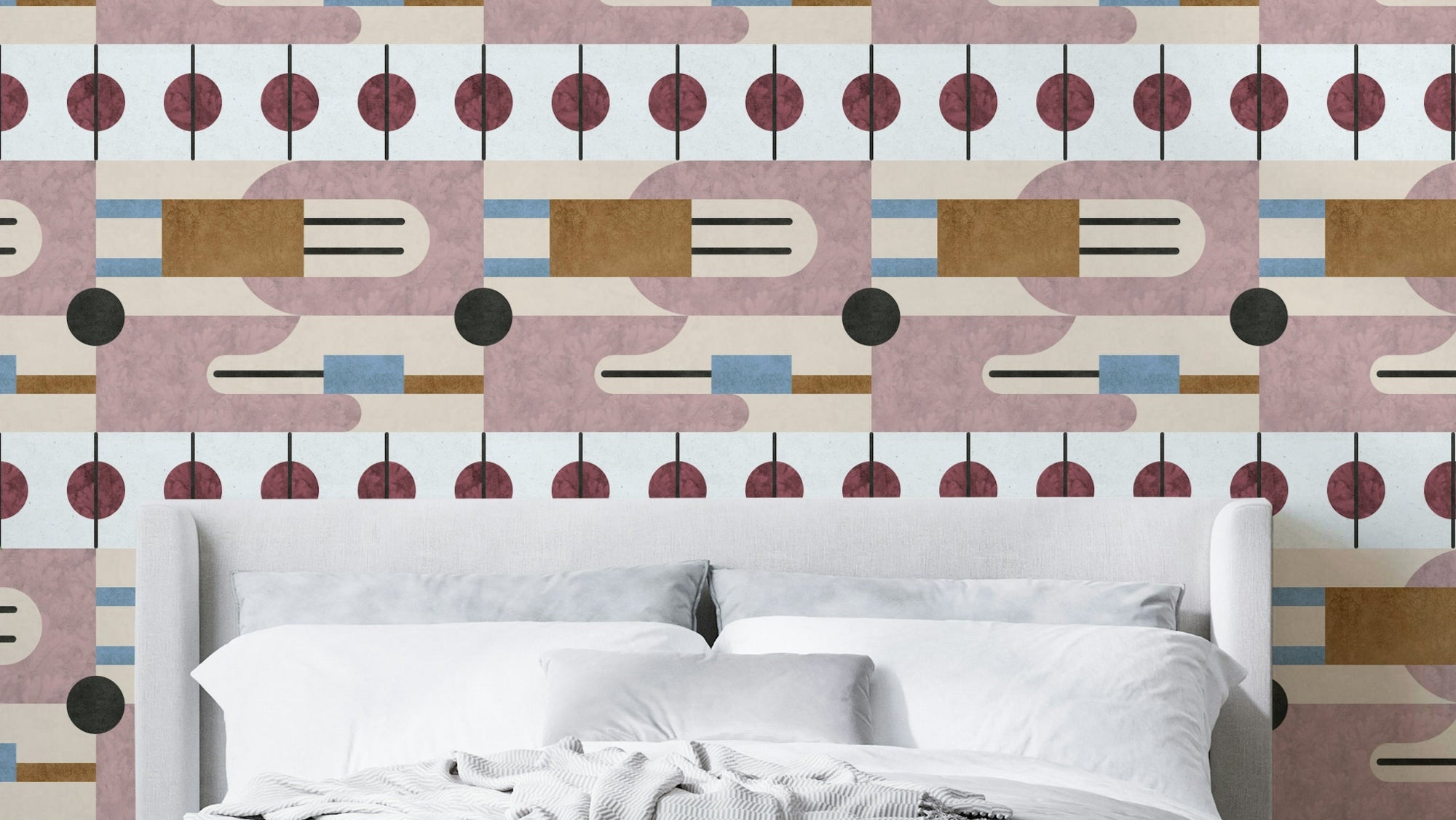 Serene Geometry wallpaper in mauve and burgundy atomic shapes behind a white upholstered bed with white linens