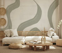 Subtle Stream wallpaper mural in sage green behind a low cream sofa with rattan poufs in a boho living room