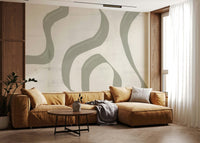 Subtle Stream wallpaper mural in sage green behind a caramel leather sectional and round wood coffee table