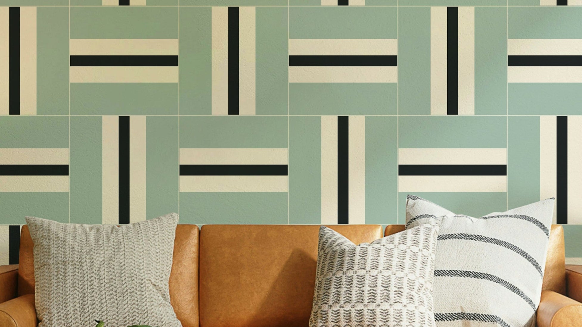 Serene Stripes wallpaper in sage green with black and cream woven tiles above a tan leather sofa
