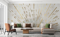 Aurora Gleam Abstract wallpaper mural of gold rays on cream behind a cream sectional sofa and orange armchair in a living room