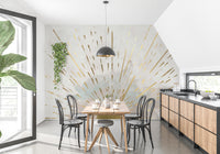 Aurora Gleam Abstract wallpaper mural of golden sunburst rays on cream behind a wood dining table and black chairs in a dining room