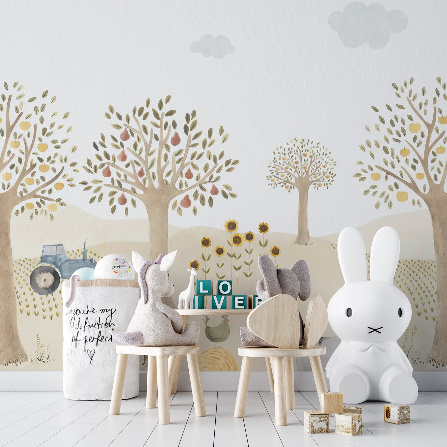 Countryside Whimsy wallpaper mural of orchard trees and a tractor behind bunny-shaped chairs and a white bunny lamp in a kids room