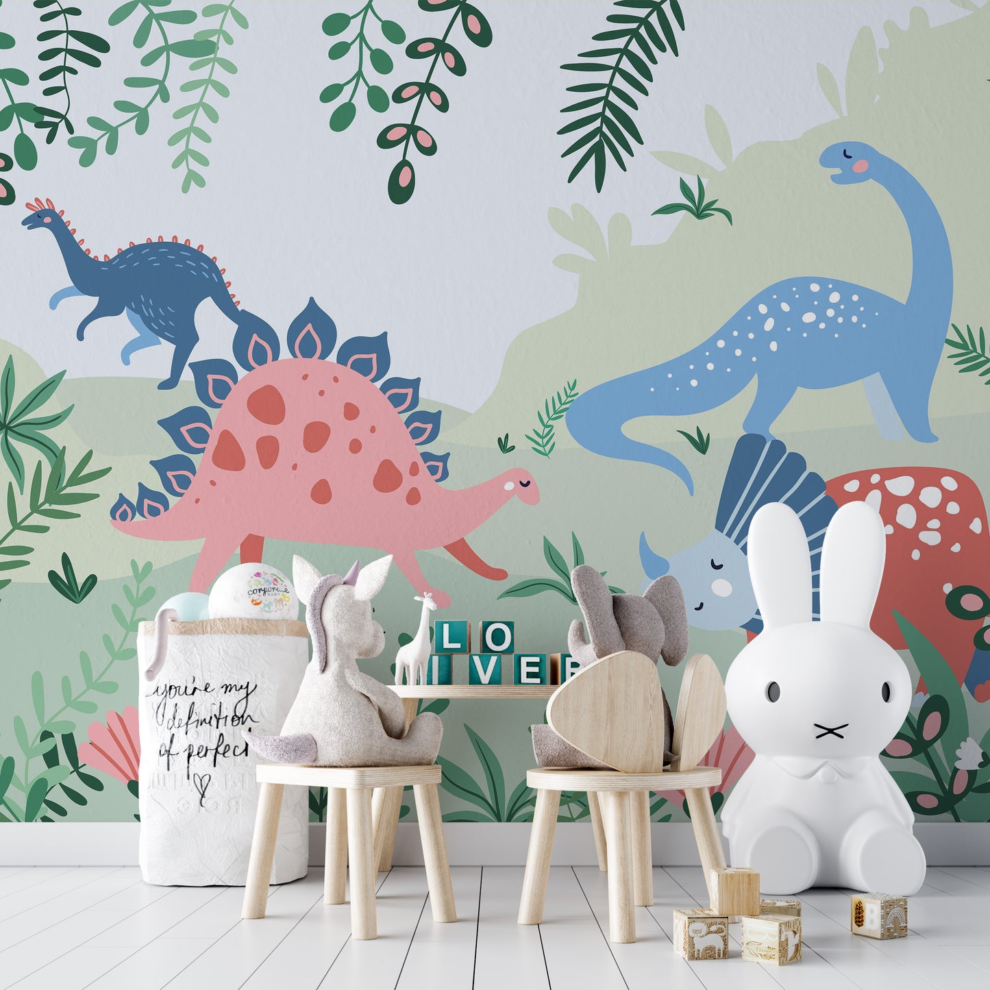 Kids Dinosaur wallpaper mural with green foliage and dinosaurs behind a wooden play table and Miffy lamp in a kids room