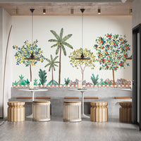 Colorful Tree Wall mural of palms and fruit trees above white bistro tables and rattan stools in a cafe