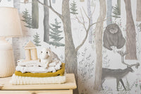Mystical Forest Scene wallpaper mural of watercolor birch woods with a bear and deer beside stacked knit blankets and a lamb plush