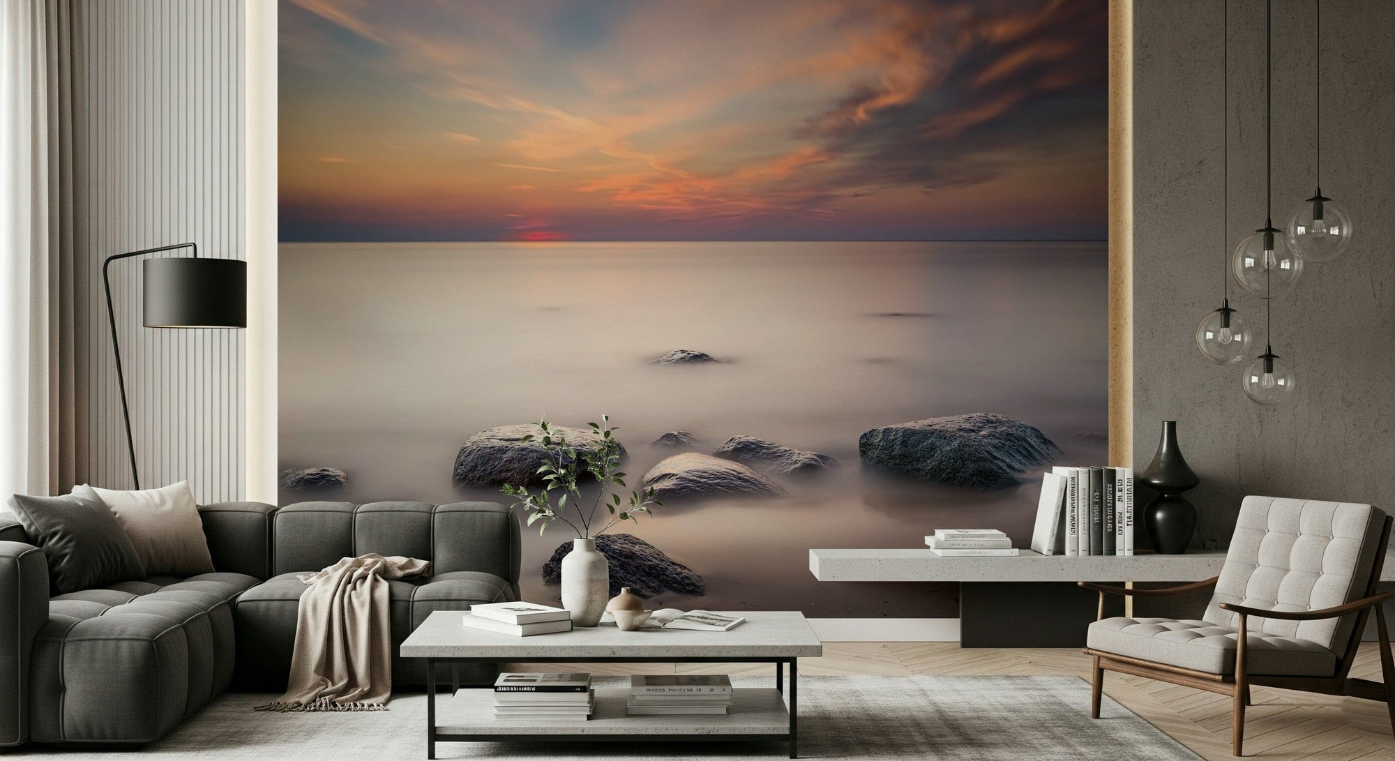 Shoreline Stillness wallpaper mural of a calm sunset sea with rocks behind a charcoal sofa and cream tufted armchair