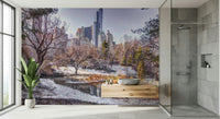 Snowy Central Park mural in a bathroom with a stone vessel sink on a wood vanity beside a glass shower