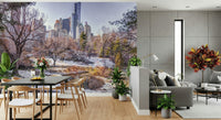 Snowy Central Park mural behind a black dining table and wood chairs near a concrete wall and croton plant