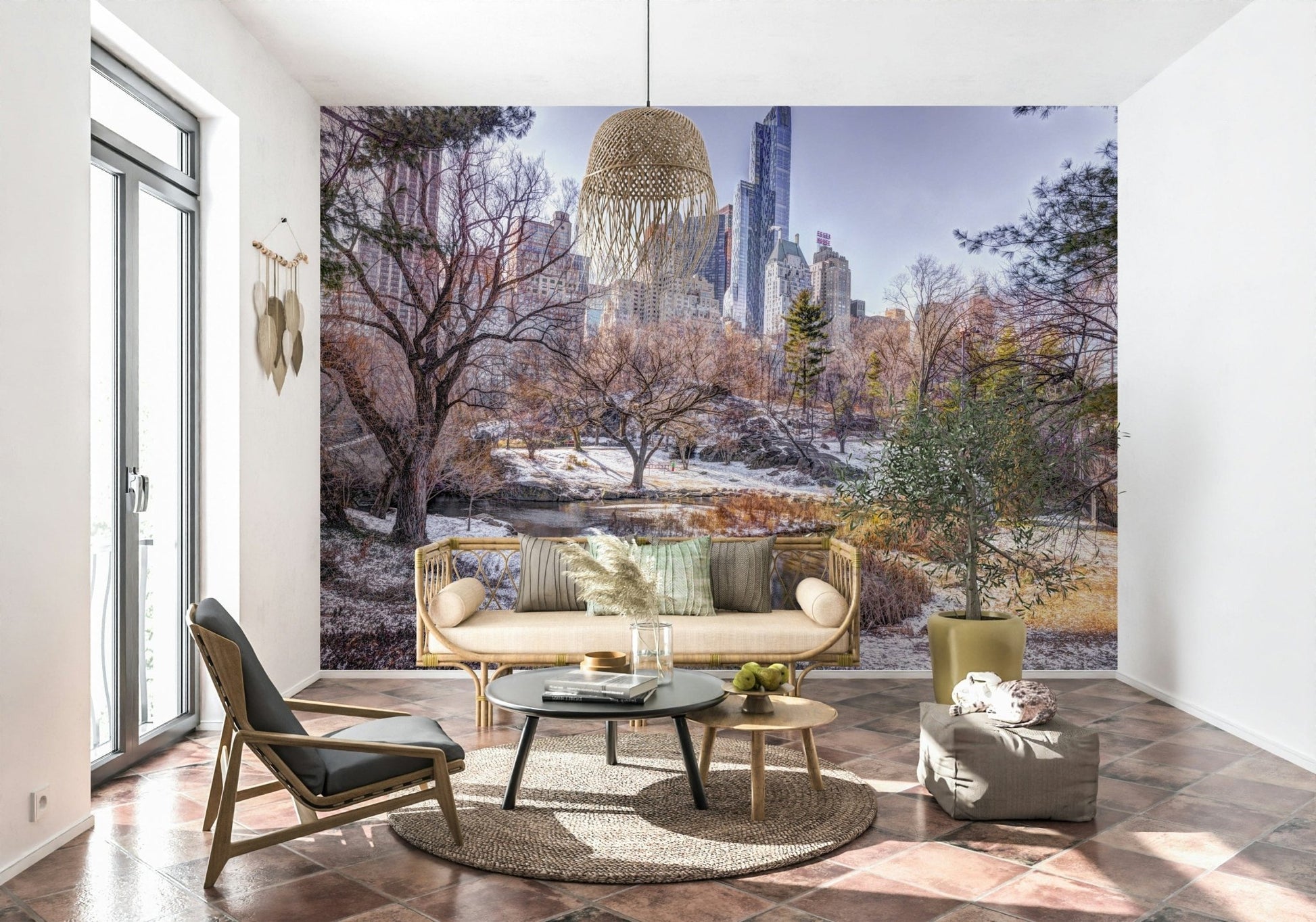 Snowy Central Park mural behind a rattan sofa with round black and wood tables and a potted olive plant