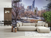 Snowy Central Park mural behind a beige sofa and chaise beside a dining area with a wood-slat divider