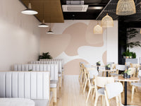 Soft Pastel Abstract wallpaper mural in blush shapes along white booth seating in a modern cafe with rattan lights